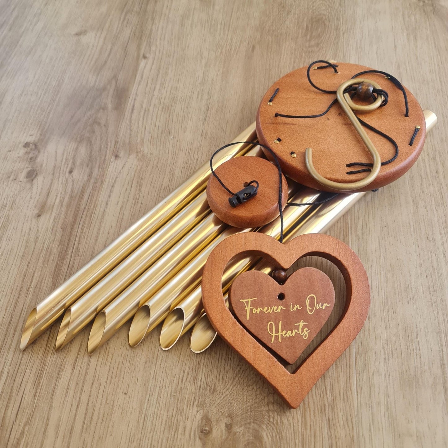Decorative metal wind chimes with wooden heart-shaped plaque on a wooden surface