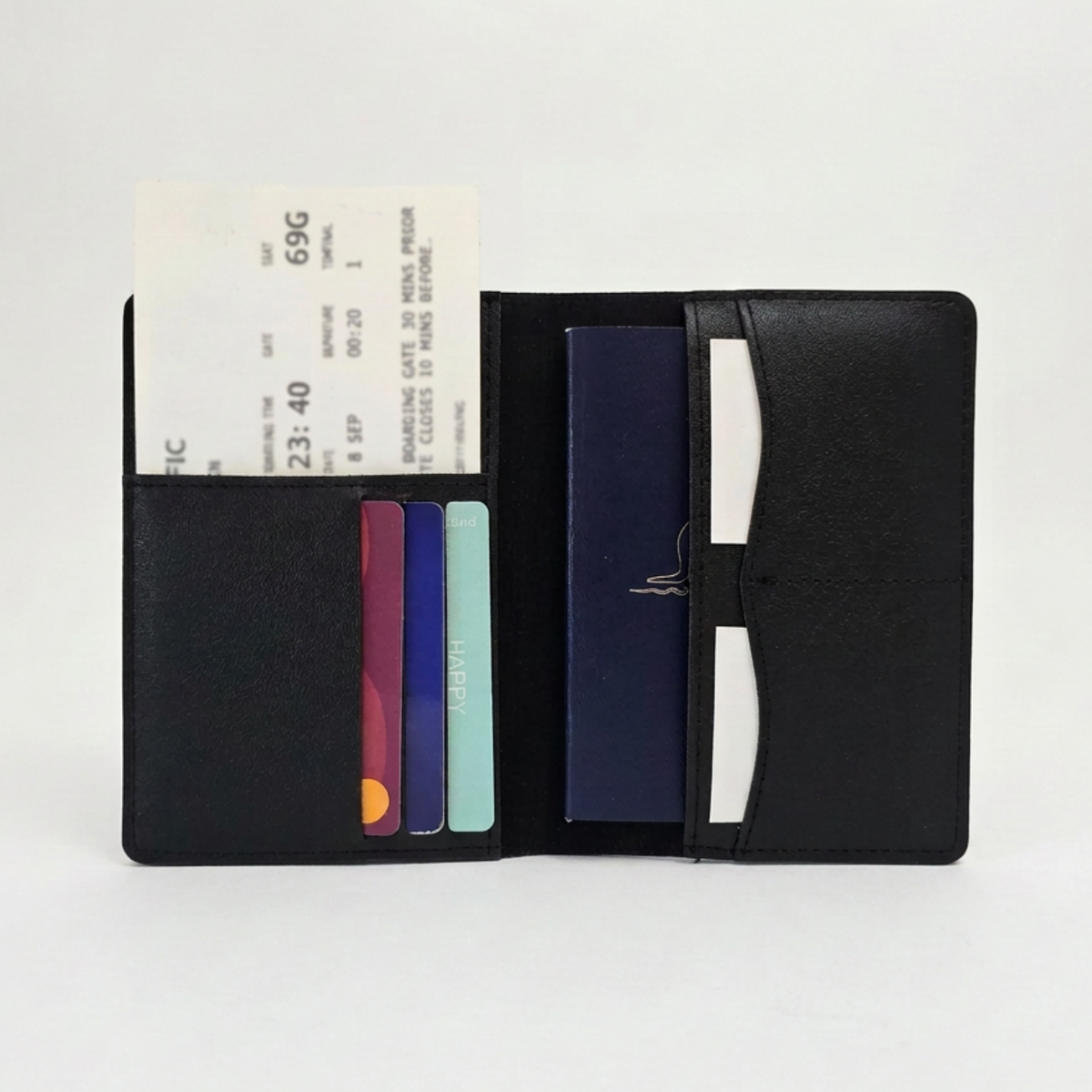 Open black passport organiser holding a passport, three cards and a boarding pass in its interior pockets.