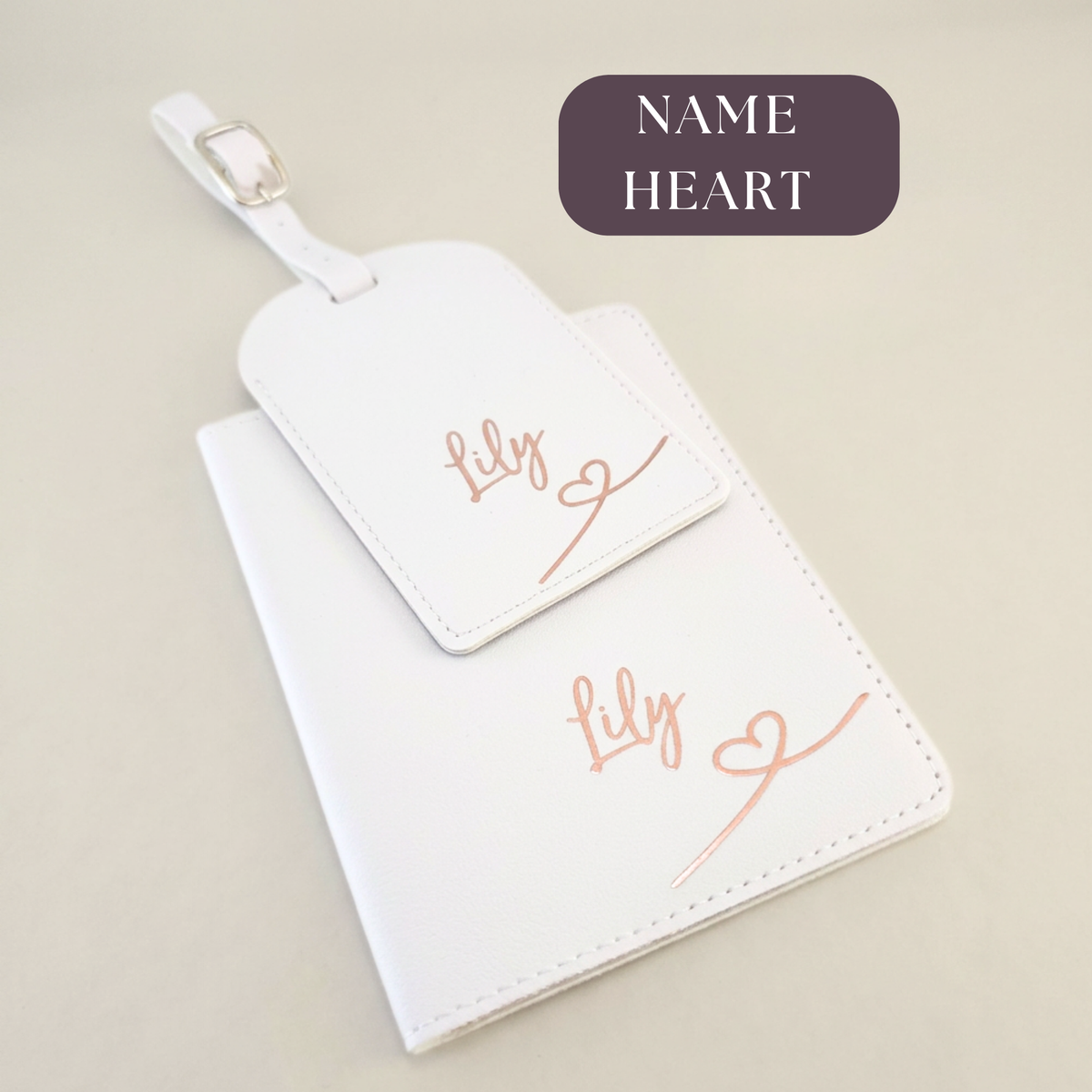 White passport organiser and matching luggage tag with rose-gold name Lily and a heart-line design.